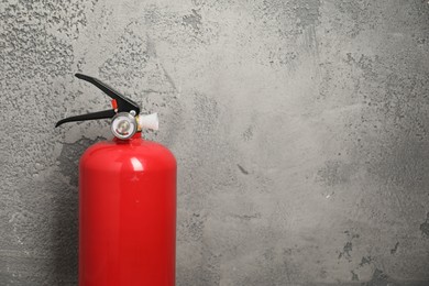 Photo of Fire extinguisher on grey textured background, space for text