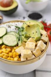 Delicious poke bowl with vegetables, tofu, avocado and microgreens served on white table, closeup