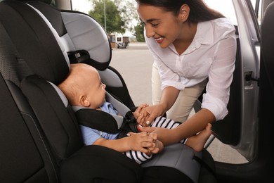 Photo of Mother fastening her son in child safety seat inside car