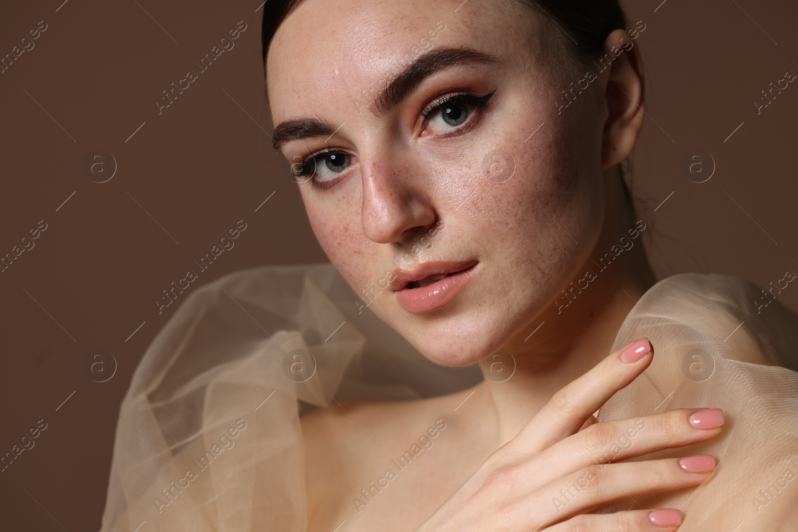 Photo of Fashionable portrait of beautiful woman with fake freckles on brown background, closeup
