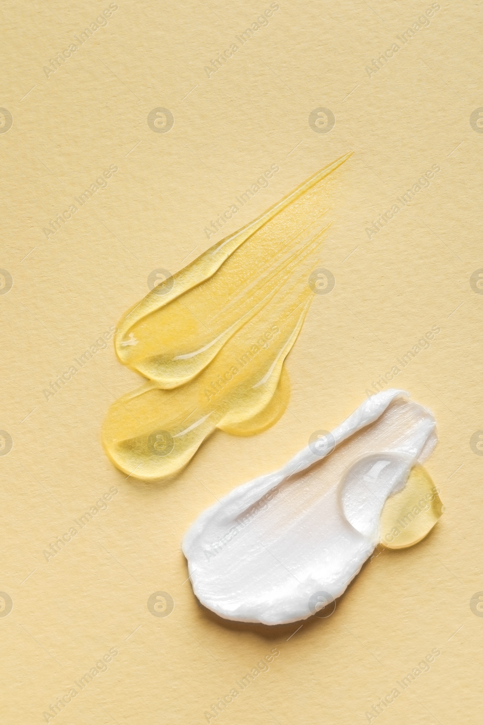 Photo of Samples of transparent gel and white cream on yellow background, flat lay