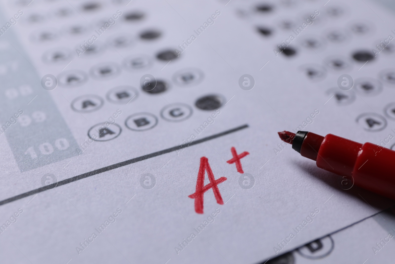 Photo of School grade. Letter A with plus symbol on answer sheet and red marker, closeup