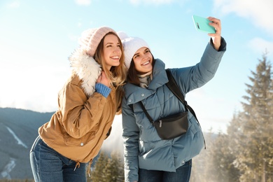 Photo of Friends taking selfie in mountains during winter vacation
