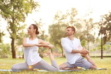 Photo of Young couple practicing yoga in park at morning