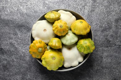 Fresh ripe pattypan squashes in bowl on grey table, top view