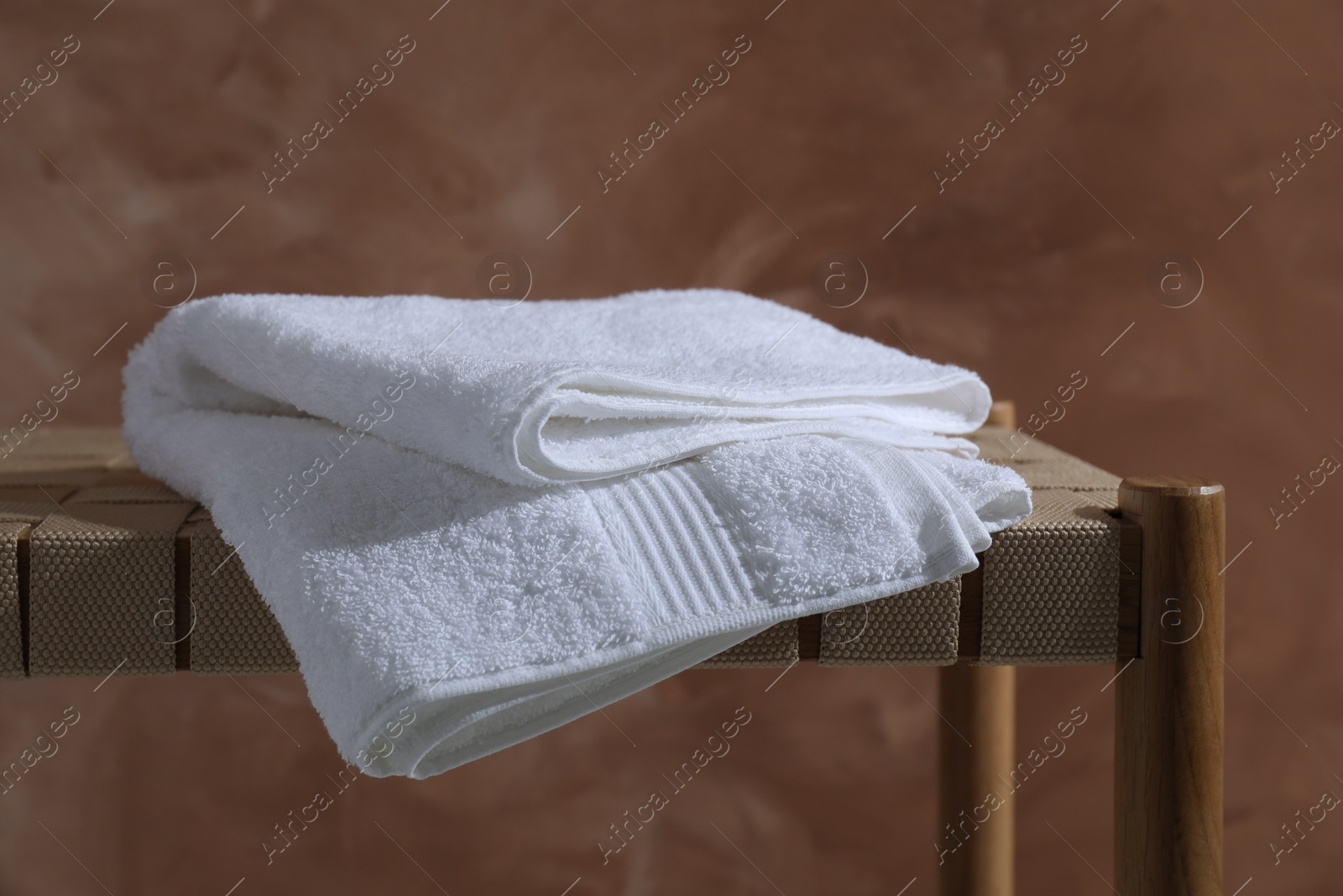 Photo of Clean towel on table against brown background, closeup