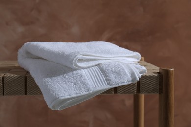 Clean towel on table against brown background, closeup