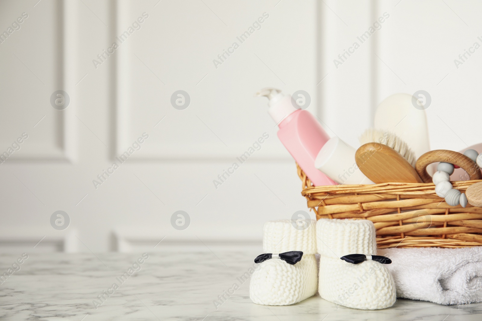 Photo of Baby booties and accessories on white marble table indoors. Space for text