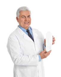 Male orthopedist showing insole on white background