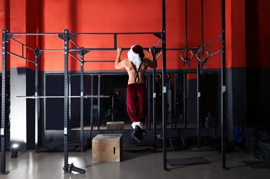 Young shirtless Santa Claus training in modern gym, back view