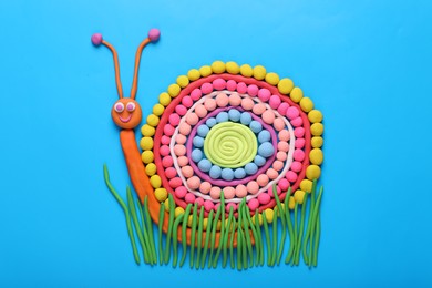 Colorful plasticine snail on light blue background, top view