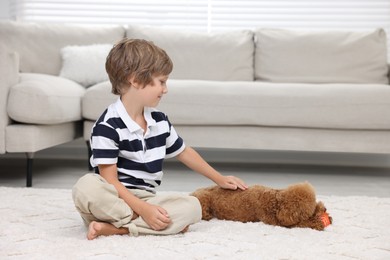 Photo of Little child and cute puppy on carpet at home. Lovely pet