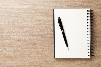 Notebook and pen on wooden table, top view. Space for text