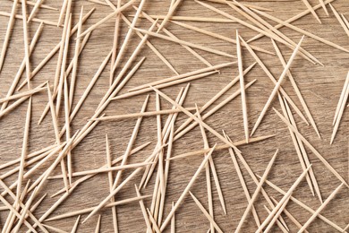 Disposable toothpicks on wooden background, flat lay