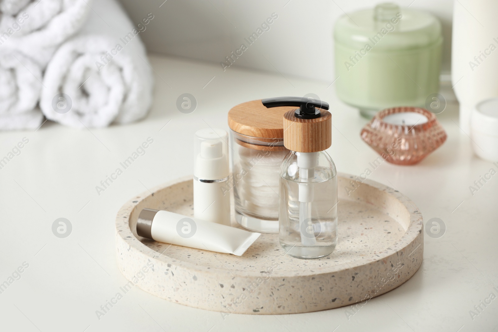 Photo of Tray with dispenser bottle and cosmetic products on white table in bathroom