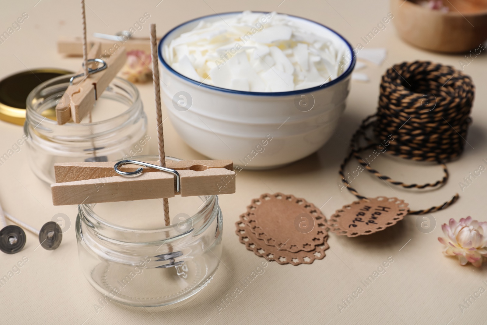 Photo of Glass jars with wicks and clothespins as stabilizers on beige background. Making homemade candles