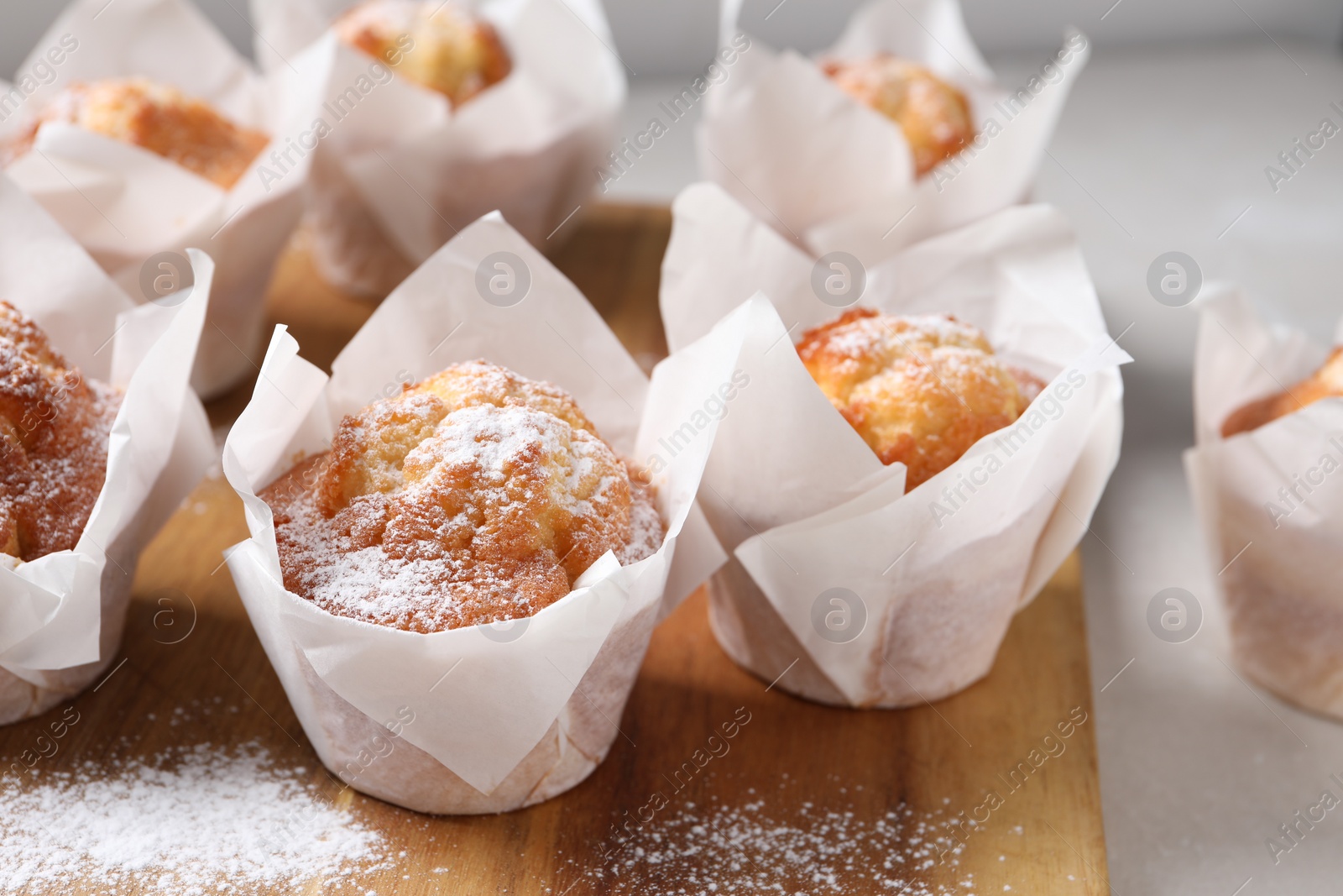 Photo of Delicious muffins with powdered sugar on table, closeup