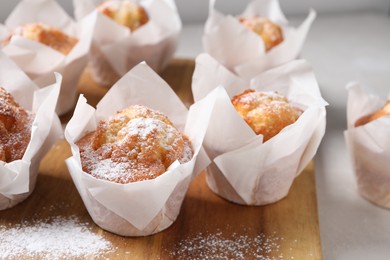 Delicious muffins with powdered sugar on table, closeup