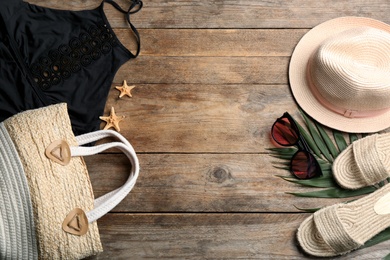 Swimsuit, bag and beach accessories on wooden table, flat lay. Space for text