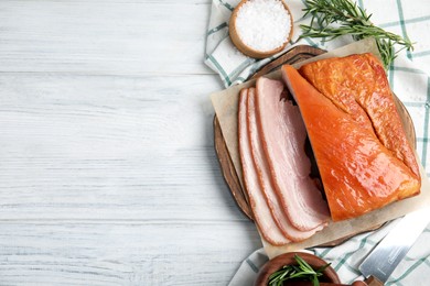 Photo of Delicious smoked bacon with rosemary and salt on white wooden table, flat lay. Space for text