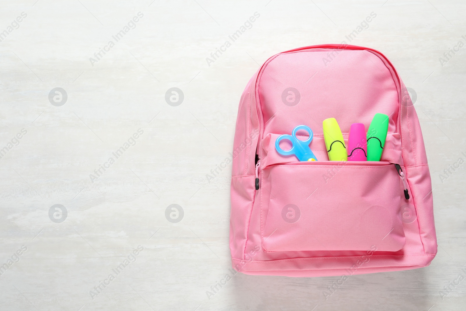 Photo of Backpack with school stationery on light background, top view and space for text