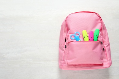 Photo of Backpack with school stationery on light background, top view and space for text