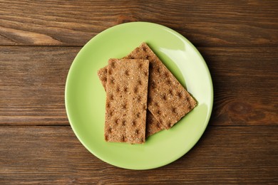 Plate with rye crispbreads on wooden table, top view