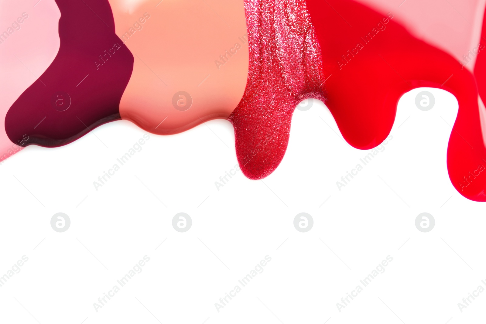 Photo of Colorful nail polishes spilled on white background