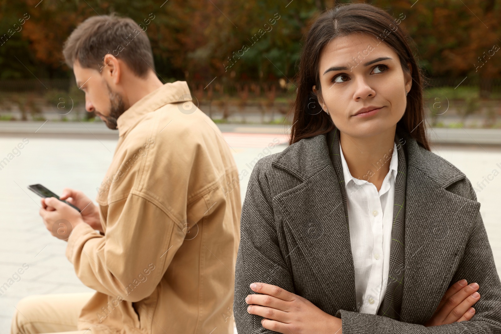 Photo of Upset arguing couple sitting on bench in park. Relationship problems