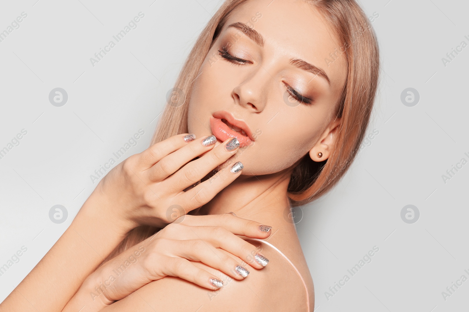 Photo of Beautiful young woman with shiny manicure on light background, closeup. Nail polish trends