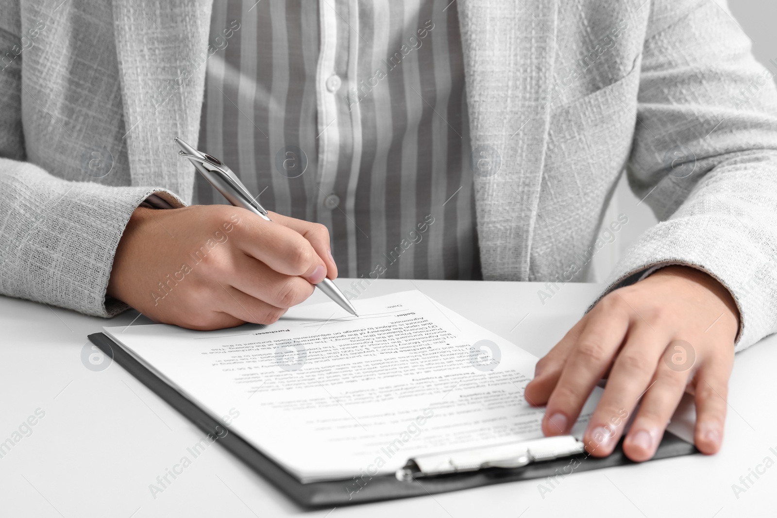 Photo of Man signing document at white table, closeup