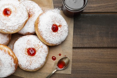 Photo of Many delicious donuts with jelly and powdered sugar on wooden table, flat lay. Space for text