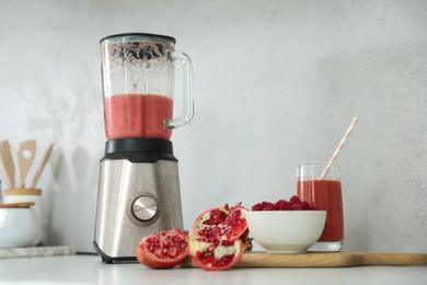 Blender and smoothie ingredients on white table in kitchen