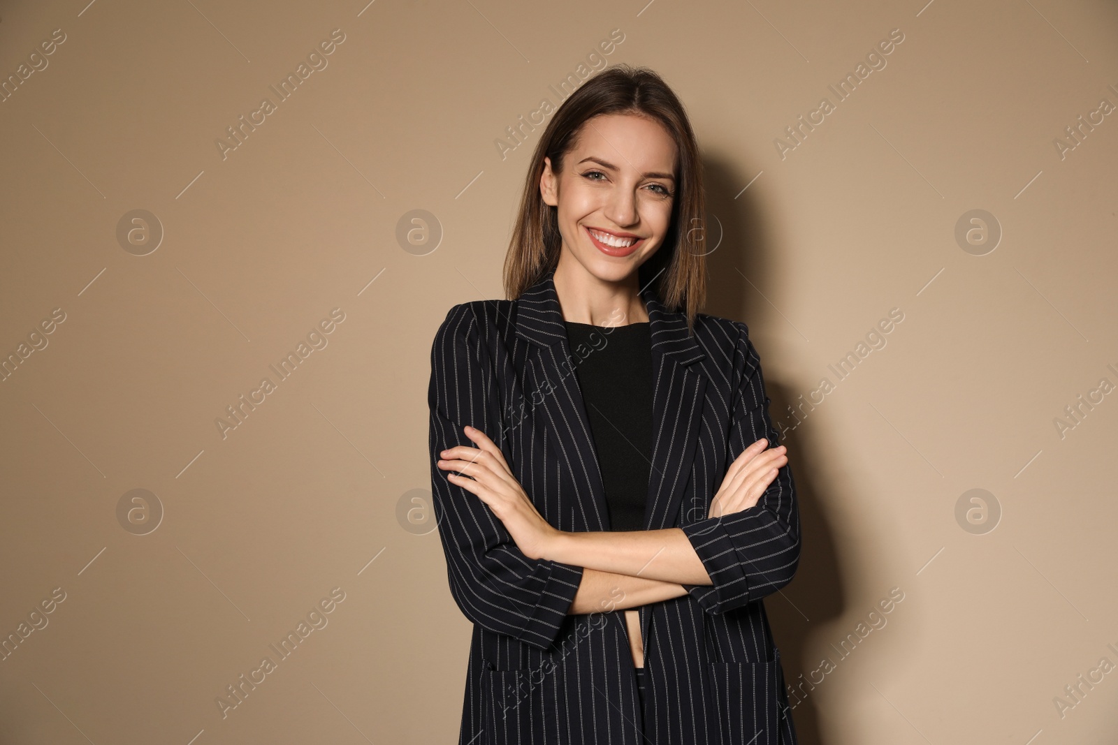 Photo of Portrait of beautiful young woman in fashionable suit on beige background. Business attire