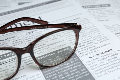 Photo of Glasses on newspaper, closeup view. Search concept