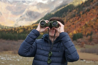 Photo of Boy looking through binoculars in beautiful mountains