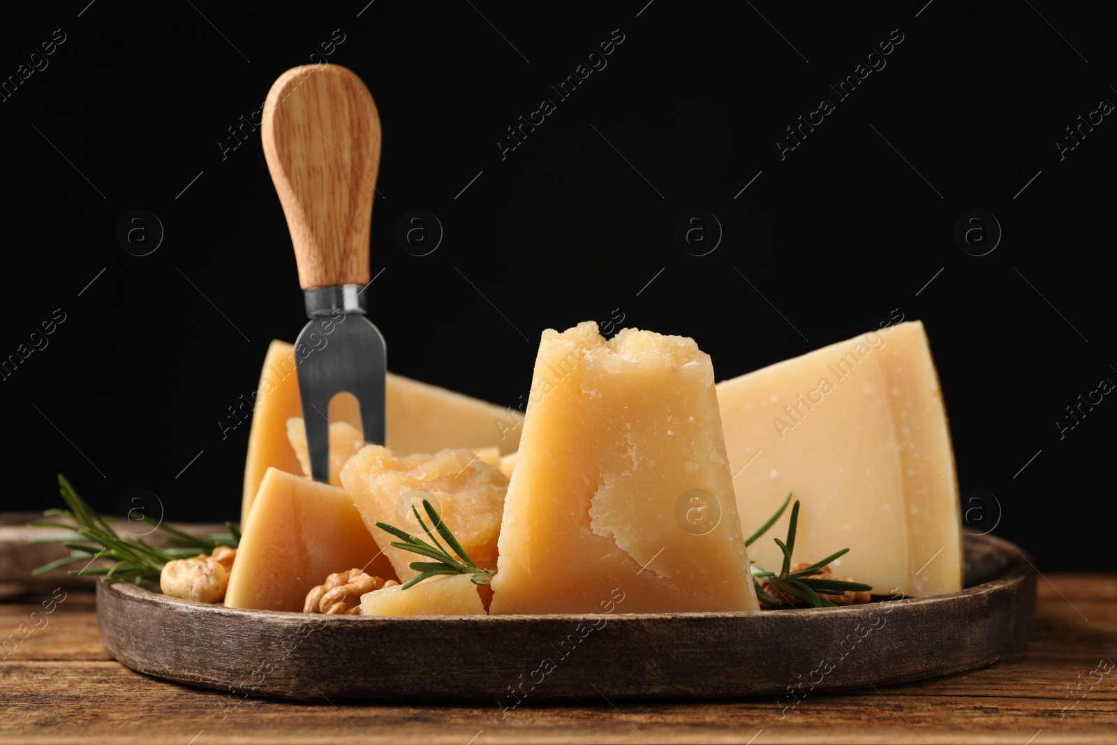 Photo of Delicious parmesan cheese with rosemary on wooden table