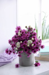 Photo of Beautiful flowers, books and violet cloth on white table
