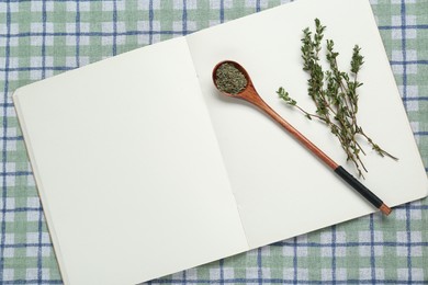 Photo of Blank recipe book and thyme on checkered tablecloth, top view. Space for text