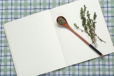 Blank recipe book and thyme on checkered tablecloth, top view. Space for text