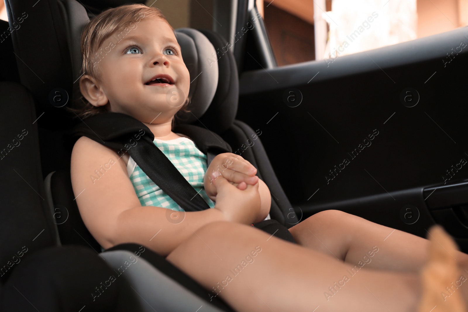 Photo of Cute little girl sitting in child safety seat inside car