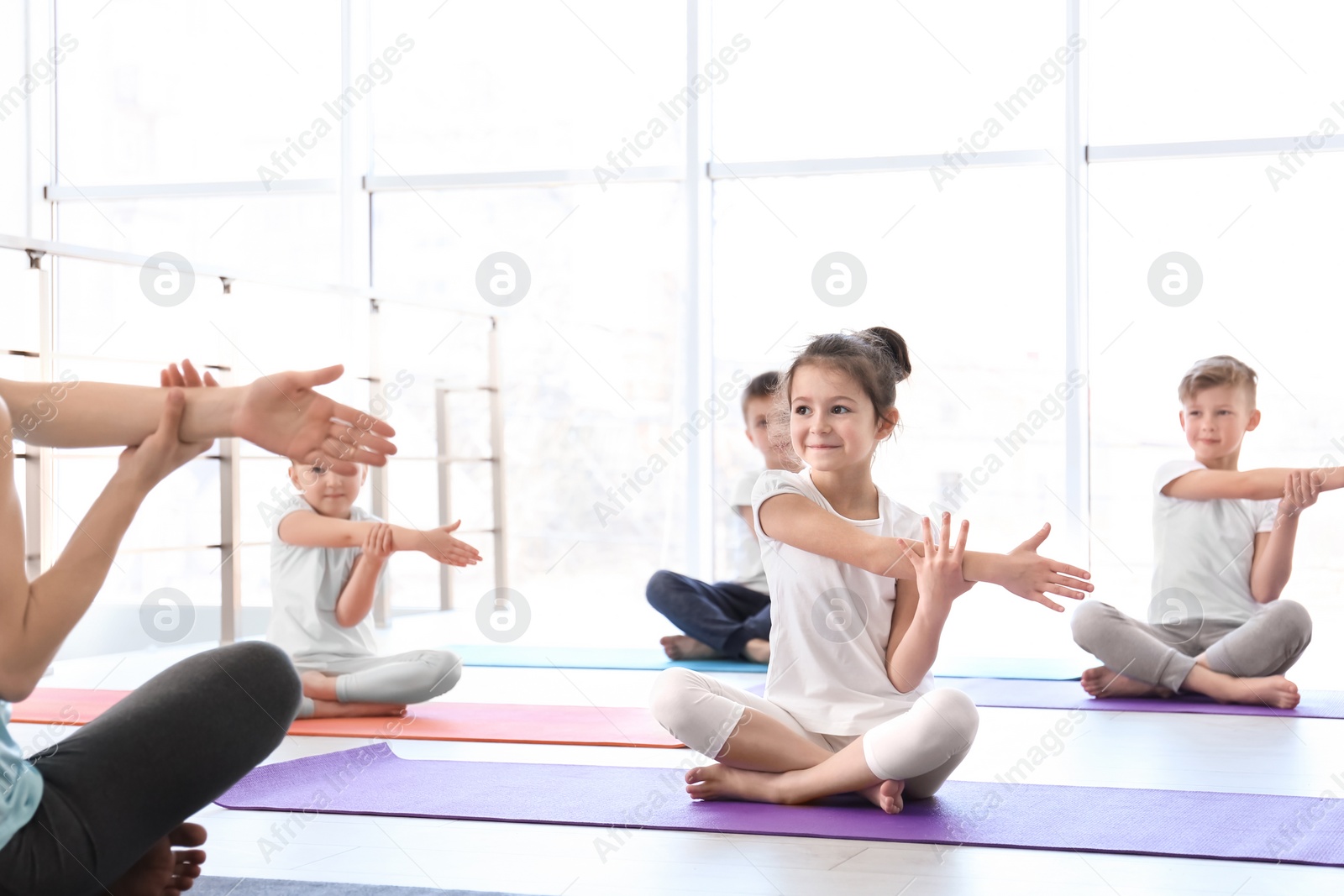 Photo of Little children and their teacher practicing yoga in gym