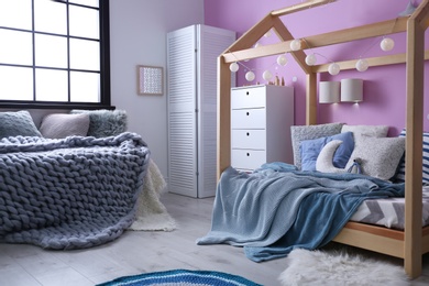 Child's room interior with comfortable bed and garland