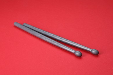 Two gray drum sticks on red background