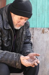 Poor homeless senior man holding coins outdoors