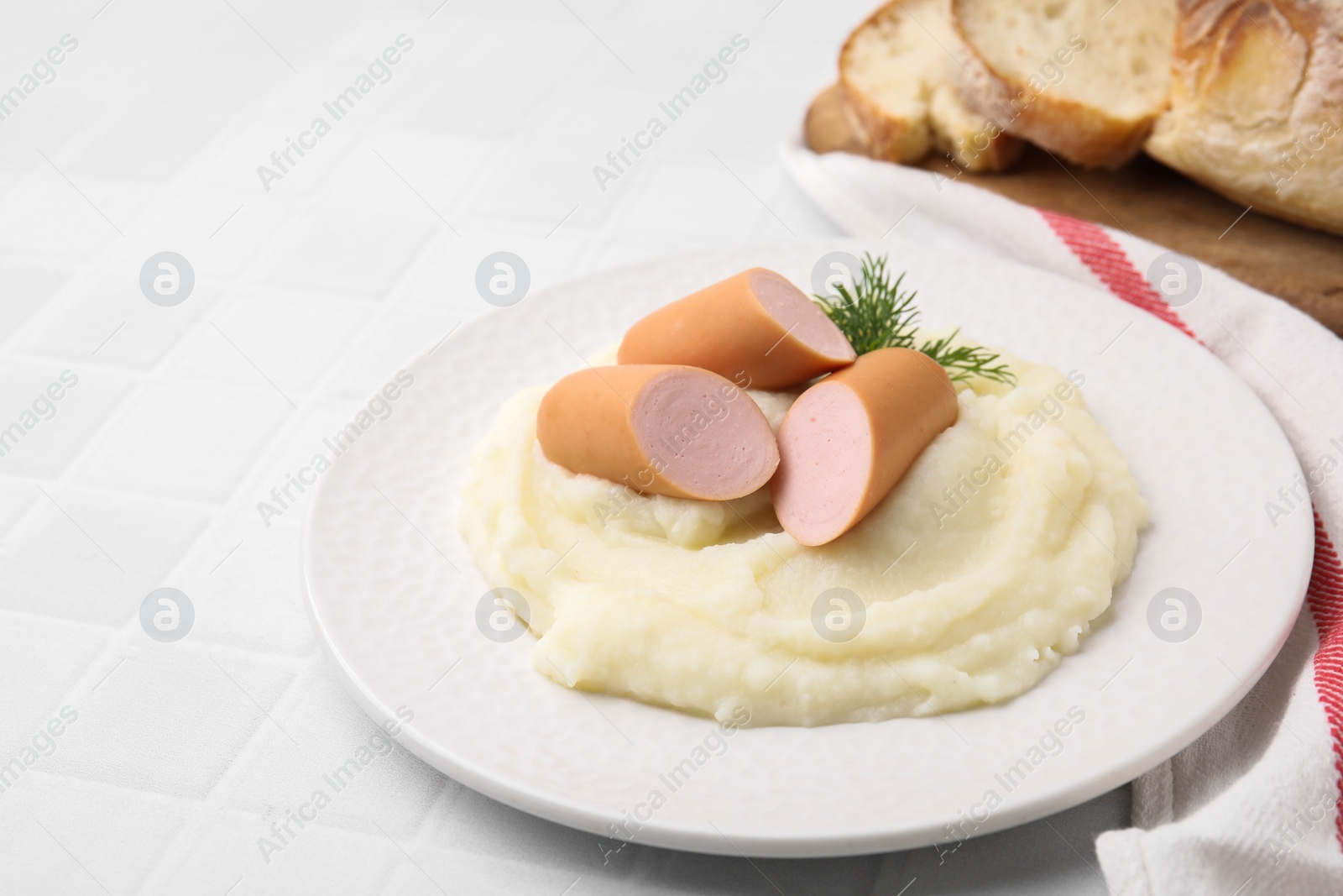 Photo of Delicious boiled sausages and mashed potato on white tiled table, closeup