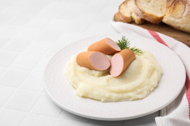 Photo of Delicious boiled sausages and mashed potato on white tiled table, closeup