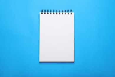 Photo of Open notebook on light blue background, top view