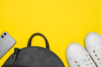 Photo of Stylish casual backpack, smartphone and sneakers on yellow background, flat lay. Space for text
