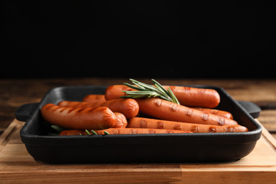 Photo of Delicious grilled sausages with rosemary on wooden table